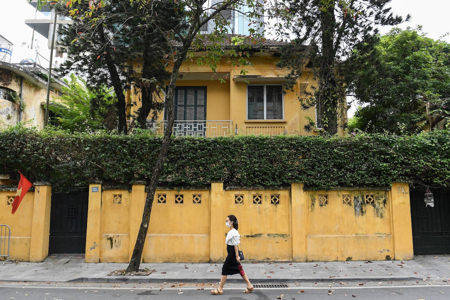 This photo taken on November 17, 2022 shows a woman walking past an old villa in Hanoi. Most of the hundreds of French-style, century-old villas in central Hanoi have been degraded by age and humidity, and despite their protected status the future of these homes and their occupants hang in the balance, as residents struggle to afford their upkeep.