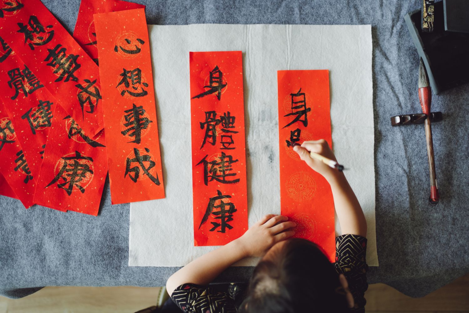 Top view of Asian little girl practicing Chinese calligraphy for Chinese New Year Fai Chun (Auspicious Messages) .