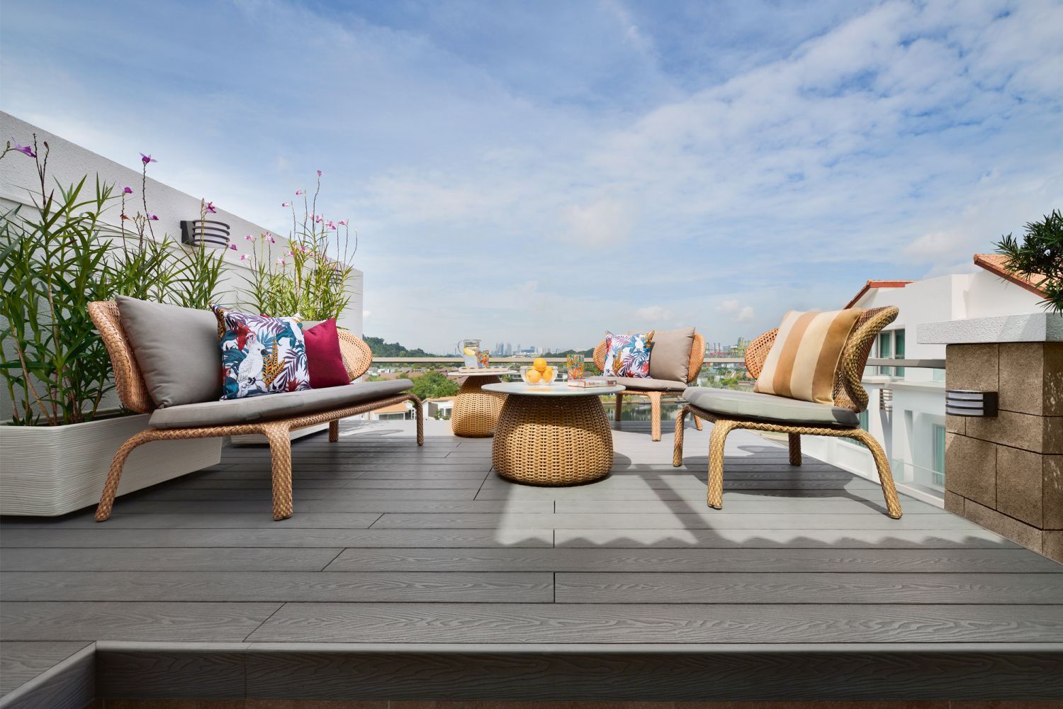 Accent cushions with tropical prints and rattan outdoor furnishings create an inviting spot that looks out to the sea