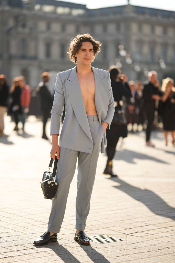 PARIS, FRANCE - OCTOBER 04: Cody Fern wears a pale gray blazer jacket, pale gray suit pants, a black shiny leather embossed LV monogram pattern handbag from Louis Vuitton, black shiny leather open toe-cap / loafers from Louis Vuitton, outside Louis Vuitton, during Paris Fashion Week - Womenswear Spring/Summer 2023, on October 04, 2022 in Paris, France. (Photo by Edward Berthelot/Getty Images)