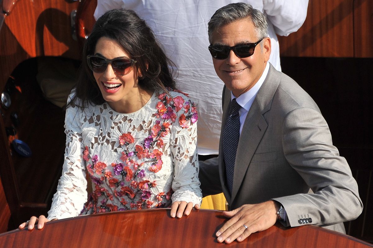 George Clooney, wearing his wedding ring, and his wife Amal Alamuddin, cruise the Grand Canal after leaving the Aman luxury Hotel in Venice, Italy, Sunday, Sept. 28, 2014. George Clooney married human rights lawyer Amal Alamuddin Saturday, the actor's representative said, out of sight of pursuing paparazzi and adoring crowds. (AP Photo/Luigi Costantini) *** Local Caption *** He put a ring on it! George Clooney shows off his wedding ring and his big beaming smile as he cruised down the Grand Canal with his n