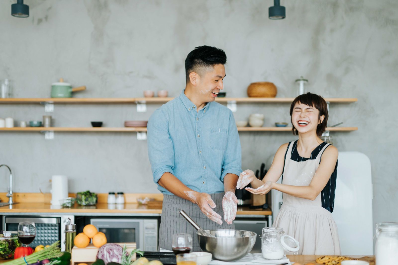 Affectionate young Asian couple having fun while baking together in a domestic kitchen
