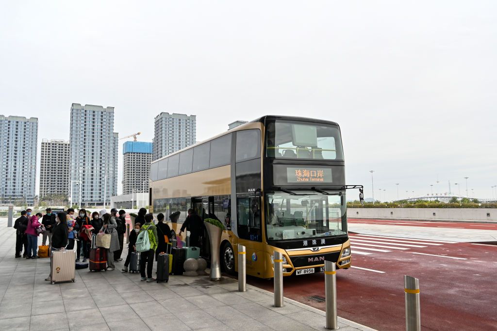 ZHUHAI, CHINA - JANUARY 08: Travellers get off a shuttle bus after arriving at Hong Kong-Zhuhai-Macao Bridge Zhuhai Port as China further optimizes its regulations on travel between the mainland and Hong Kong and Macao on January 8, 2023 in Zhuhai, Guangdong Province of China. (Photo by Chen Jimin/China News Service/VCG via Getty Images)