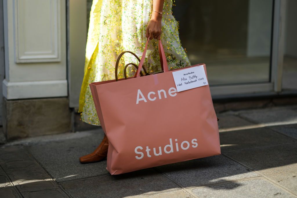 PARIS, FRANCE - SEPTEMBER 29: A guest wears a white with green embroidered sequins oversized midi dress, brown shiny leather block heels ankle boots, a gold Juste Un Clou bracelet from Cartier, a brown large shopping bag from Acne Studio, outside Cecilie Bahnsen, during Paris Fashion Week - Womenswear Spring Summer 2022, on September 29, 2021 in Paris, France. (Photo by Edward Berthelot/Getty Images)