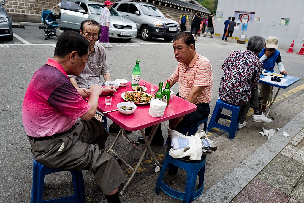 在首爾街頭邊喝燒酒邊聊天,這種低酒精度的蒸餾酒已是韓國人的日常飲料。Photo:Getty Images