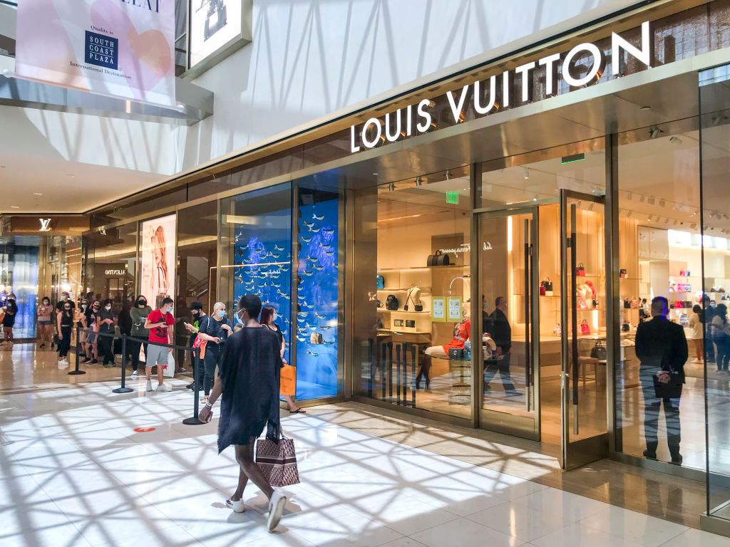 COSTA MESA, CA - JULY 13: Shoppers wear masks while waiting in line to shop at Louis Vuitton at South Coast Plaza Monday, which will be closed down Tuesday for a second time by Gov. Newsom in an attempt to slow the spread of coronavirus on Monday, July 13, 2020 in Costa Mesa, CA. California shopping malls, gyms, indoor church worship and nail salons will shut down again, Gov. Gavin Newsom announced on Monday in a new round of measures aimed at curtailing the fast-spreading coronavirus outbreak. The closure