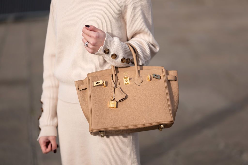 PARIS, FRANCE - MARCH 18: May Berthelot wears a white latte ribbed wool with brown buttoned sleeves pullover, a matching ribbed wool midi skirt, diamonds rings, a gold Serpenti ring from Bulgari, a beige leather Birkin handbag from Hermes, during a street style fashion photo session, on March 18, 2023 in Paris, France. (Photo by Edward Berthelot/Getty Images)