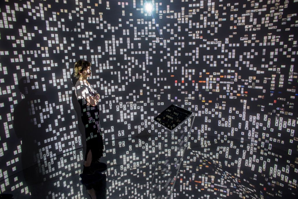 ISTANBUL, TURKEY - MAY 06:  A woman views historical documents and photographs displayed in a high tech art installation at Salt Galata on May 6, 2017 in Istanbul, Turkey. The "Archive Dreaming" installation by artist Refik Anadol uses artificial intelligence to visualize nearly 2 million historical Ottoman documents and photographs from the SALT Research Archive. Controlled by a single tablet in the center of a mirrored room the artist used machine learning algorithms to combine historical documents, art,