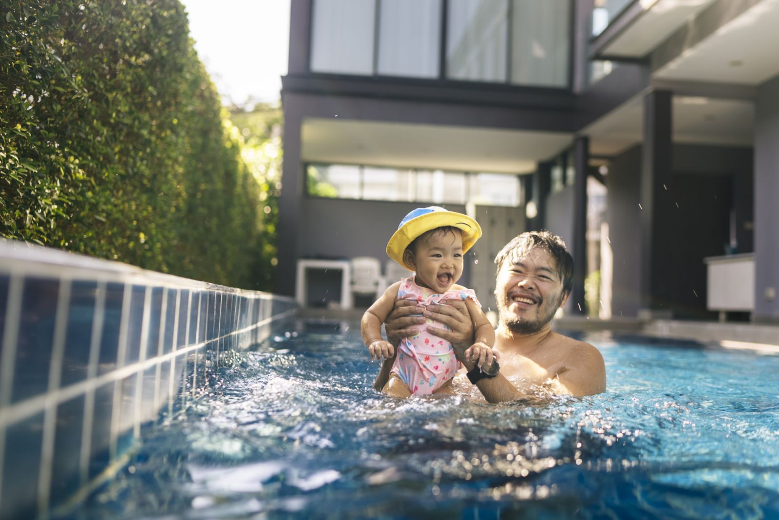 Asian father and daughter enjoyment and relaxing Summer at swimming pool domestic life