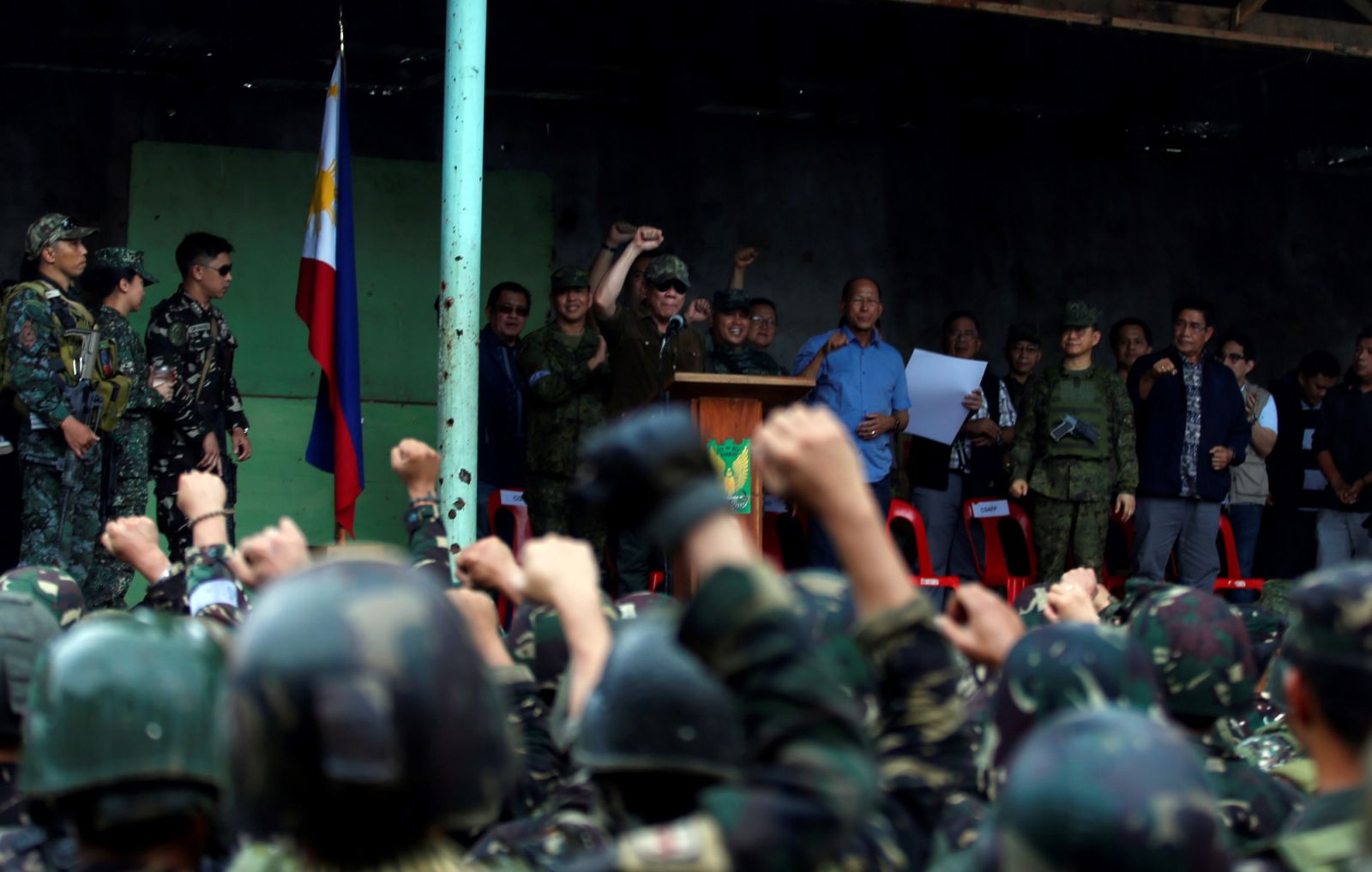 Soldiers, along with President Rodrigo Duterte, are seen during a flag raising in Marawi City in the Southern Philippines October 17, 2017. (Photo by Jeoffrey Maitem/Anadolu Agency/Getty Images)