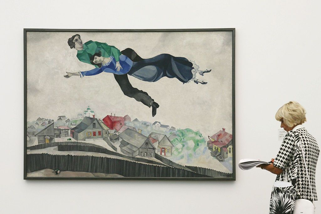 A journalist takes notes while looking at the painting "Over the City's roofs" by the Russian-French painter Marc Chagall at the Frieder Burda museum in Baden-Baden, western Germany 06 July 2006. The Chagall show contains about 100 art works and will be open to the public from 7 July to 29 October 2006. AFP PHOTO  DDP/MICHAEL LATZ   GERMANY OUT (Photo credit should read MICHAEL LATZ/DDP/AFP via Getty Images)