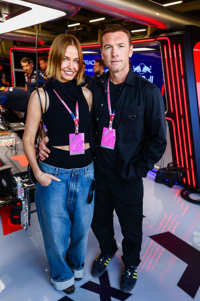 NORTHAMPTON, ENGLAND - JULY 09: Sam Worthington and Lara Worthington pose for a photo in the Red Bull Racing garage prior to the F1 Grand Prix of Great Britain at Silverstone Circuit on July 09, 2023 in Northampton, England. (Photo by Mark Thompson/Getty Images)