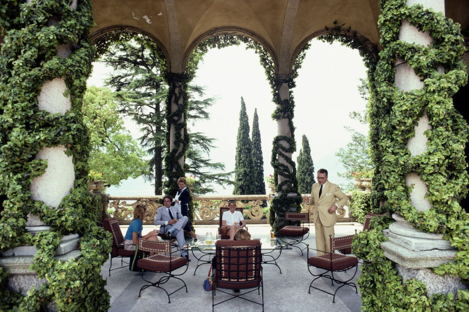 Italian mountain climber and explorer Guido Monzino (1928-1988) and four people relaxing on the terrace of Monzino's home, Villa del Balbianello in Lenno, overlooking Lake Como, Italy, in June 1983. (Photo by Slim Aarons/Getty Images)