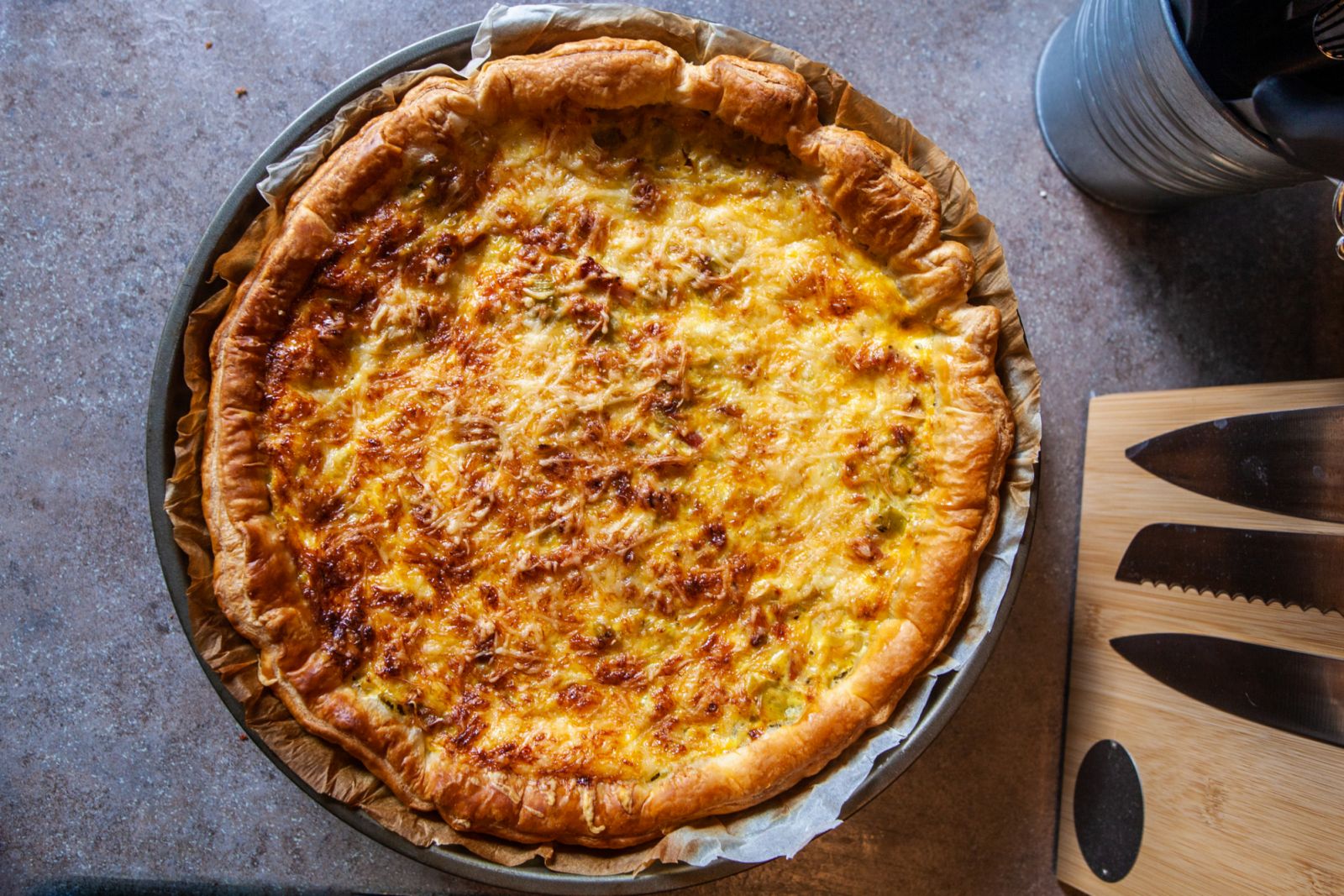 Cette photographie présente une tarte, une quiche aux poireaux à la sortie du four, dans un plat adéquat. Cuisiner des légumes, cuisine traditionnelle.
