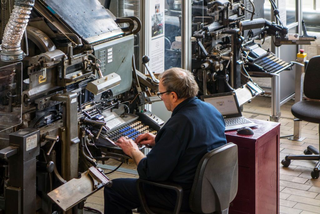Linotype machine operator enters text on a 90-character keyboard at printing business. (Photo by: Arterra/Universal Images Group via Getty Images)