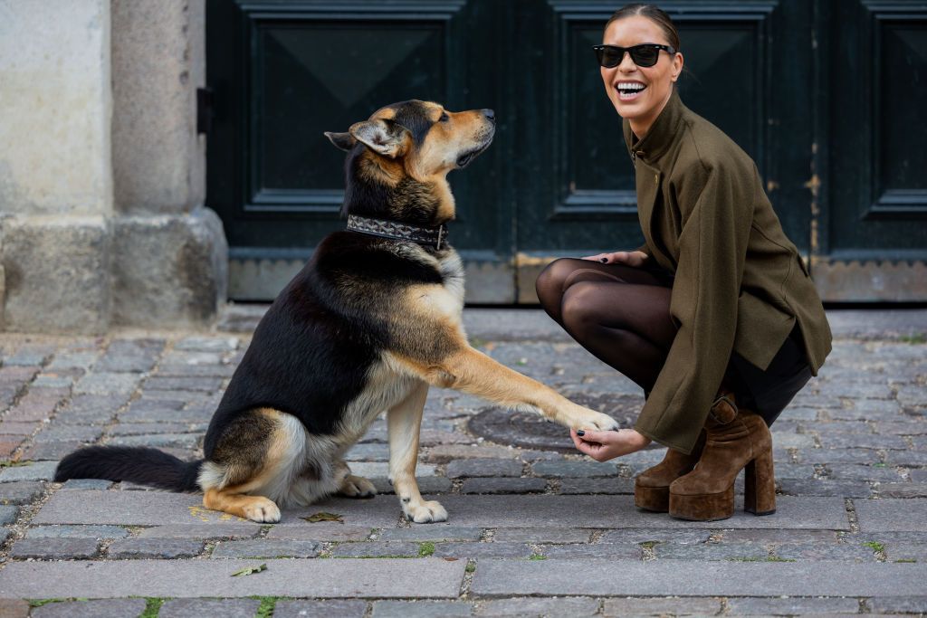 COPENHAGEN, DENMARK - AUGUST 09: A guest wears olive jacket with her dog outside Baum und Pferdgarten during the Copenhagen Fashion Week Spring/Summer 2024 on August 09, 2023 in Copenhagen, Denmark. (Photo by Christian Vierig/Getty Images)