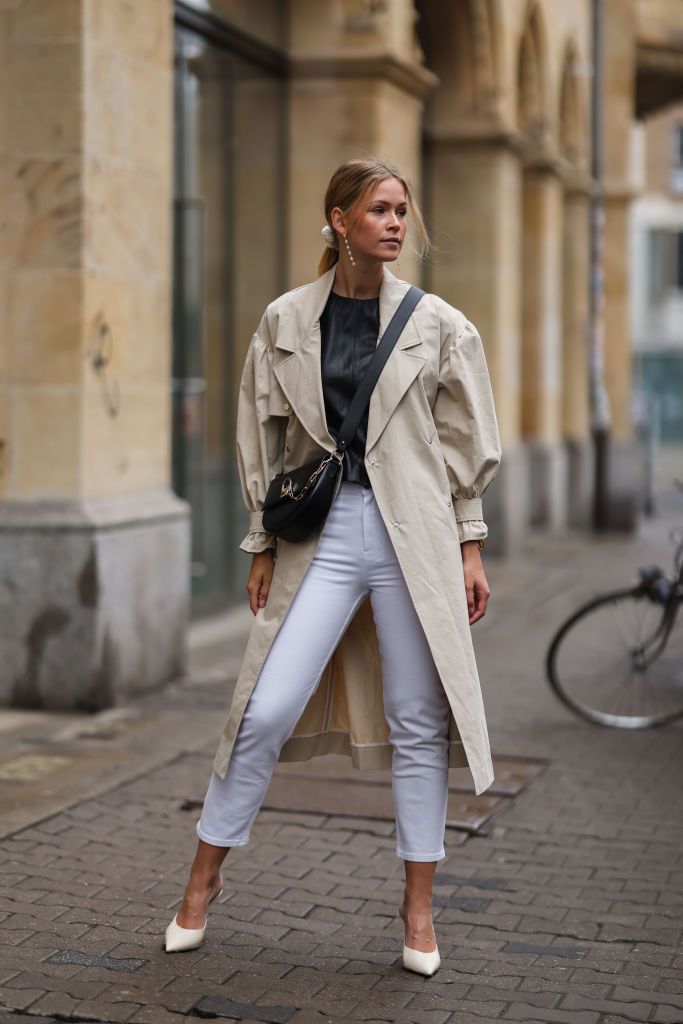 BERLIN, GERMANY - APRIL 29: Melanie Kroll wearing Jimmy Choo heels, beige ba&sh coat and black leather top, PdPaola earrings, white Tommy Hilfiger jeans and black Furla bag on April 29, 2021 in Berlin, Germany. (Photo by Jeremy Moeller/Getty Images)