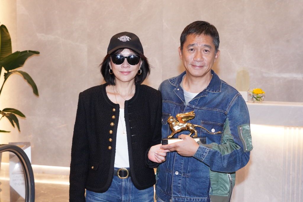 HONG KONG, CHINA - SEPTEMBER 08: Actor Tony Leung Chiu-wai and his wife Carina Lau Kar-ling pose with the trophy at Hong Kong International Airport on September 8, 2023 in Hong Kong, China. Tony Leung Chiu-wai received Golden Lion Lifetime Achievement Award during the 80th Venice International Film Festival on September 2. (Photo by VCG/VCG via Getty Images)