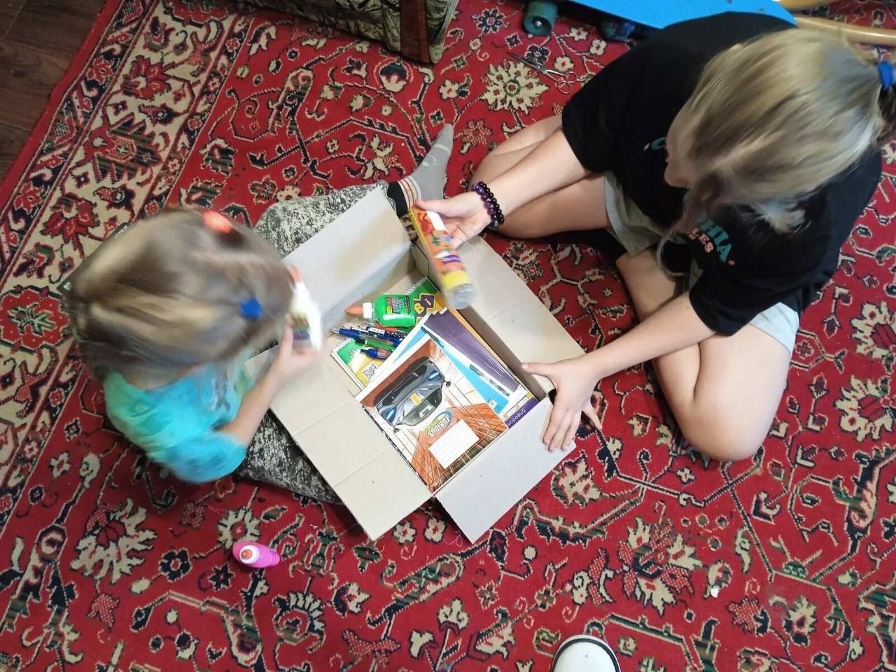 Ulyana and Varvara open the box of supplies from Children of Heroes they received in July 2023. They are using these in their classes this September