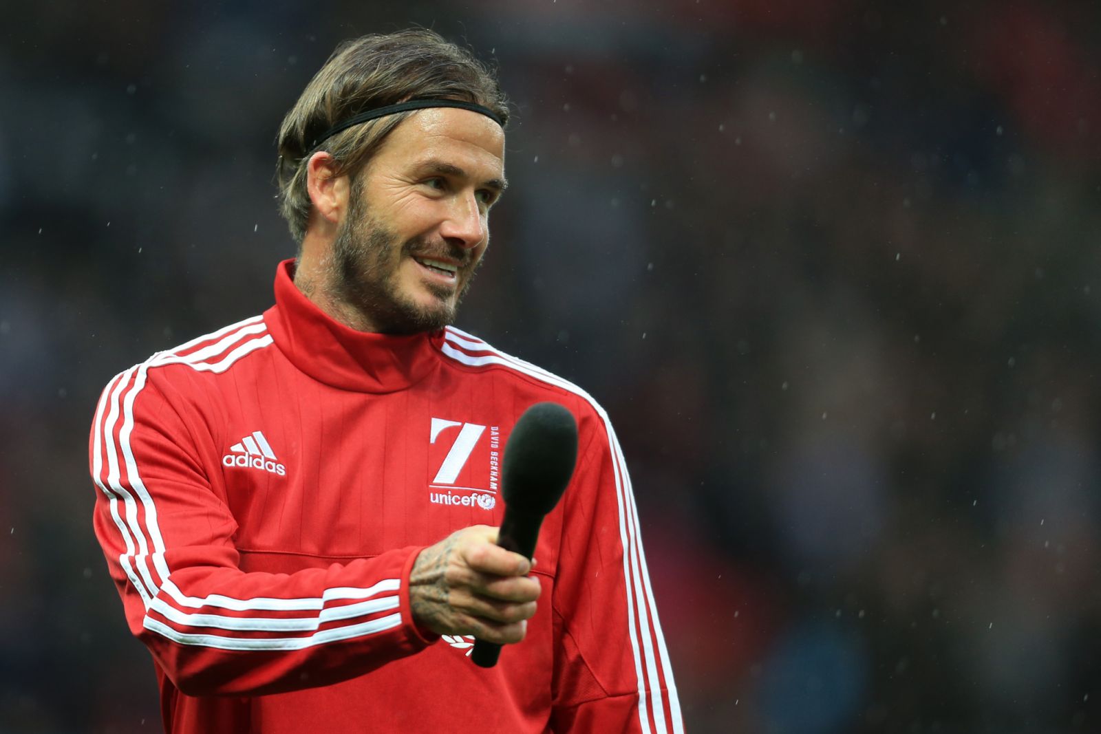David Beckham holds a microphone as he addresses the crowd before his Match For Children, in aid of UNICEF, between a Great Britain XI and a Rest of the World XI at Old Trafford on November 14, 2015 in Manchester, England (Photo by Simon Stacpoole/Mark Leech Sports Photography/Getty Images)