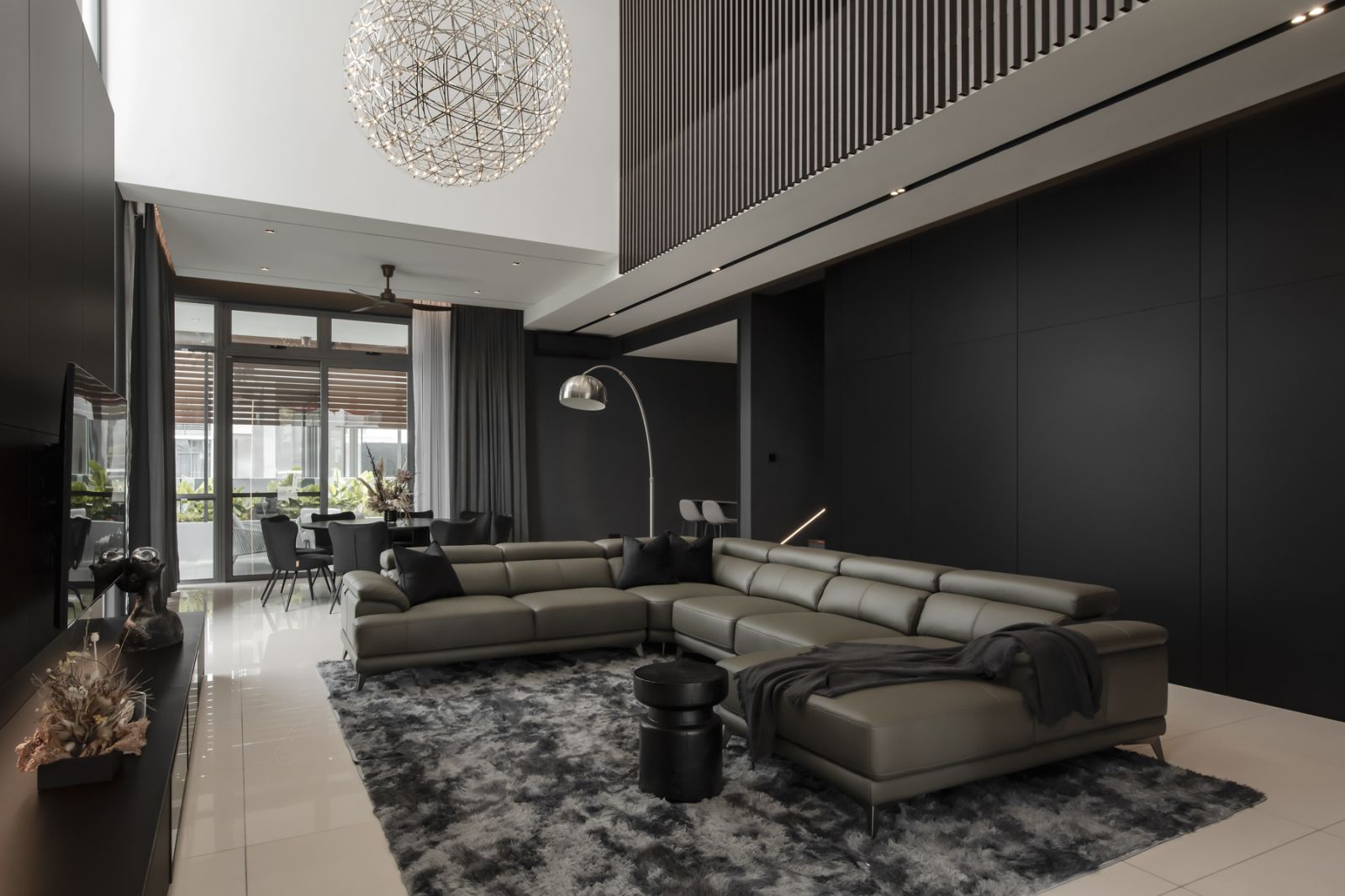 Double-height ceiling and reflective surfaces expand this expansive living room even further