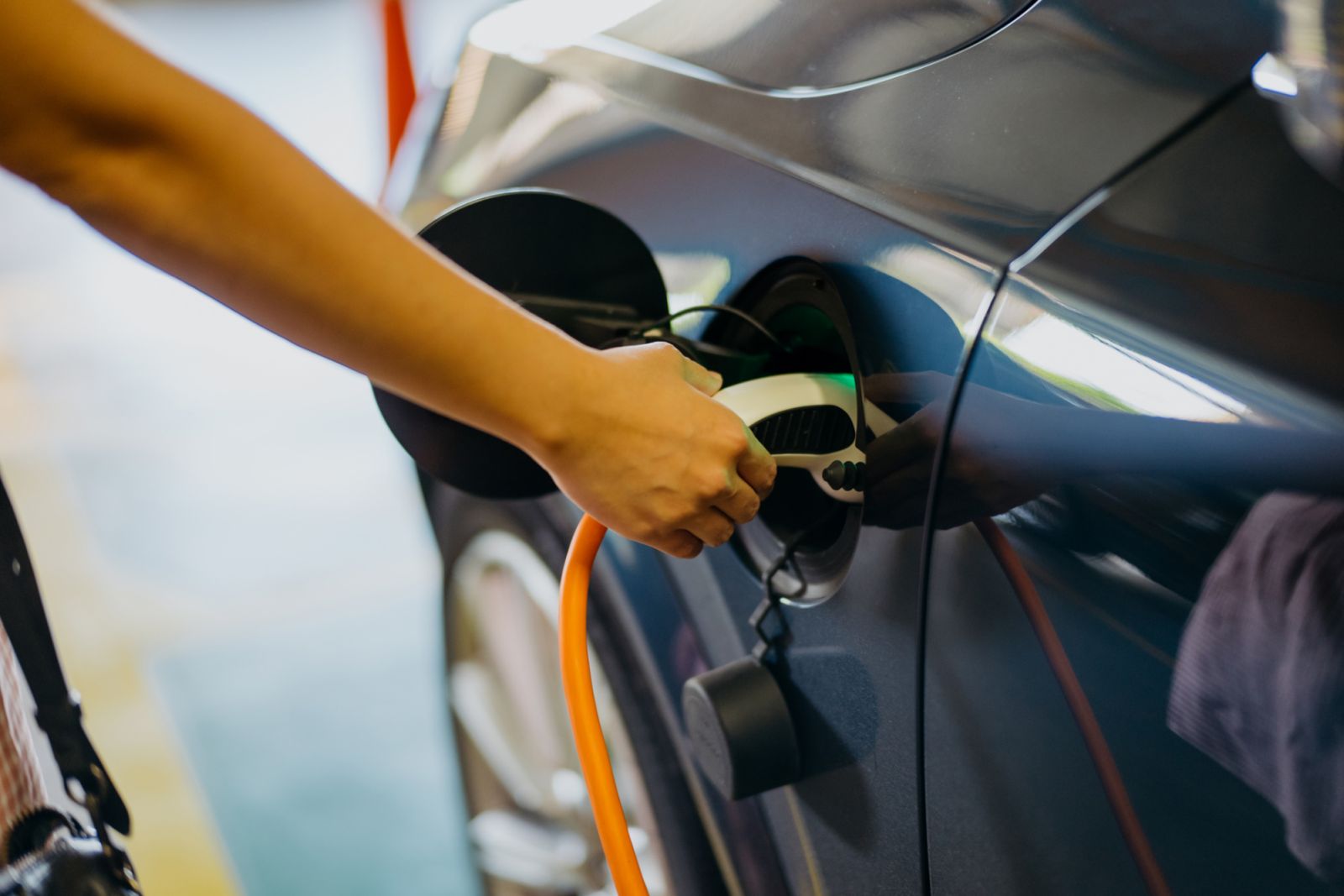 Image of an Asian Chinese woman charging her electric car at charging station