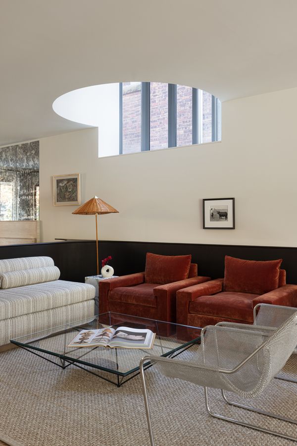 The high window and interesting placement of the skylight take advantage of natural light to illuminate the living room