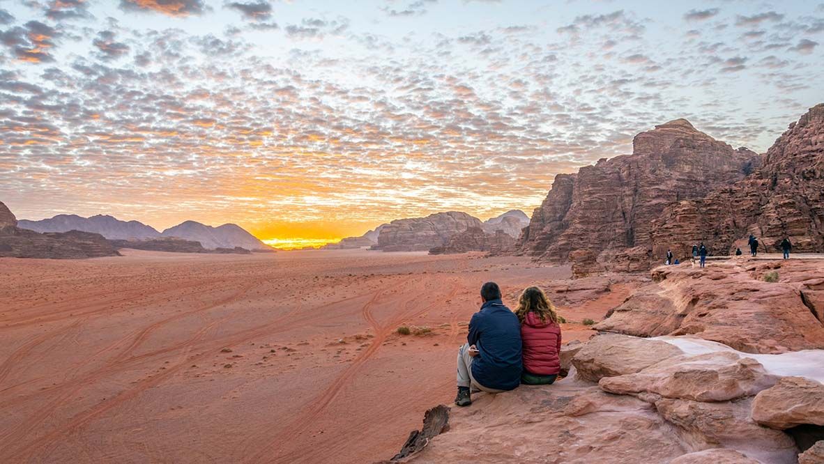 A young couple is watching at sunrise over wadi rum desert in Jordan