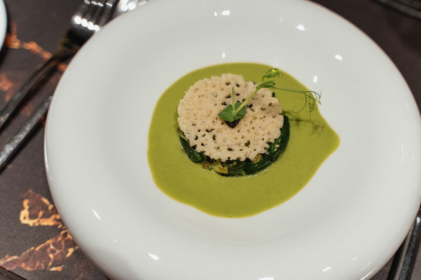 24 months old Parmigiano Reggiano garnished with baby spinach and crème of brocolli