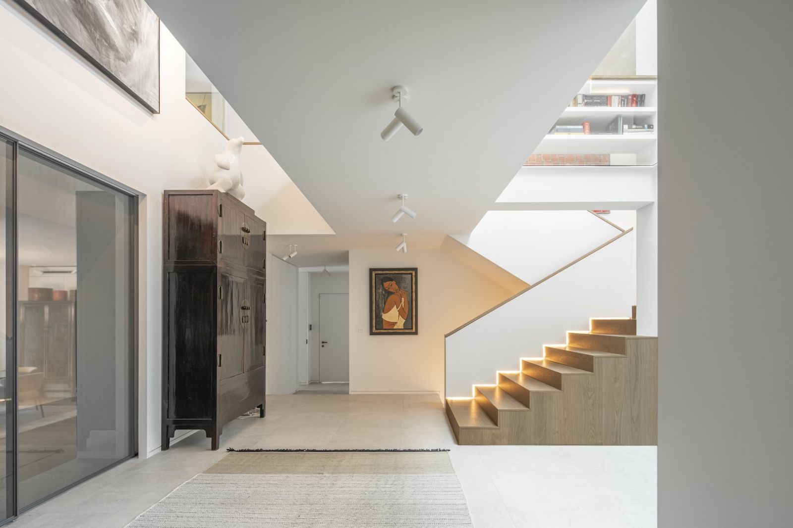 Entryway is spacious and graphic with both voids and staircase leading up to bedroom floor