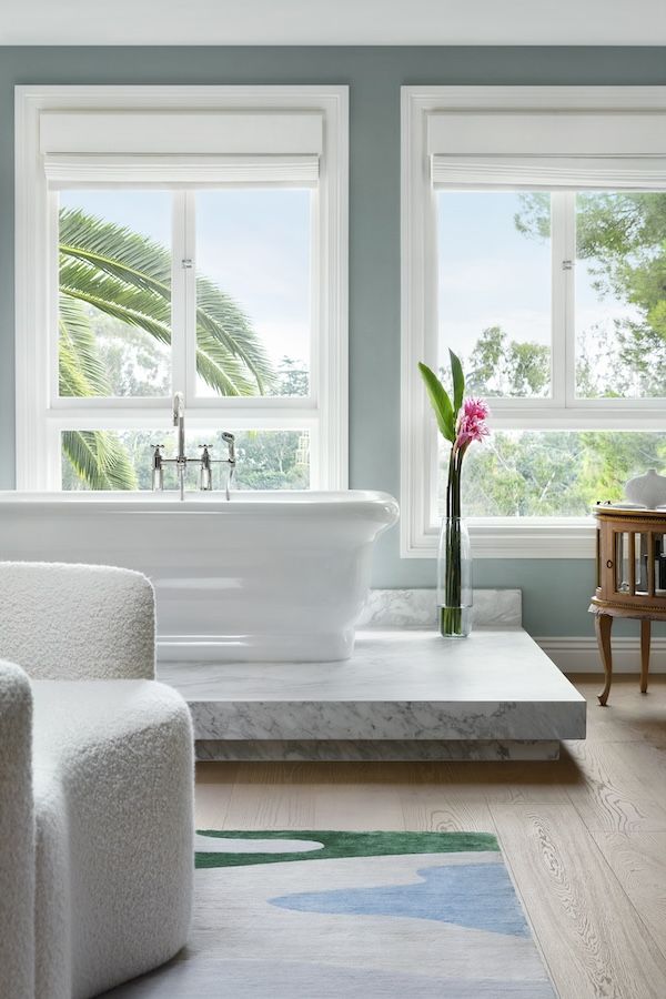 A full-sized bathtub rests upon an elevated marble platform in the master bathroom