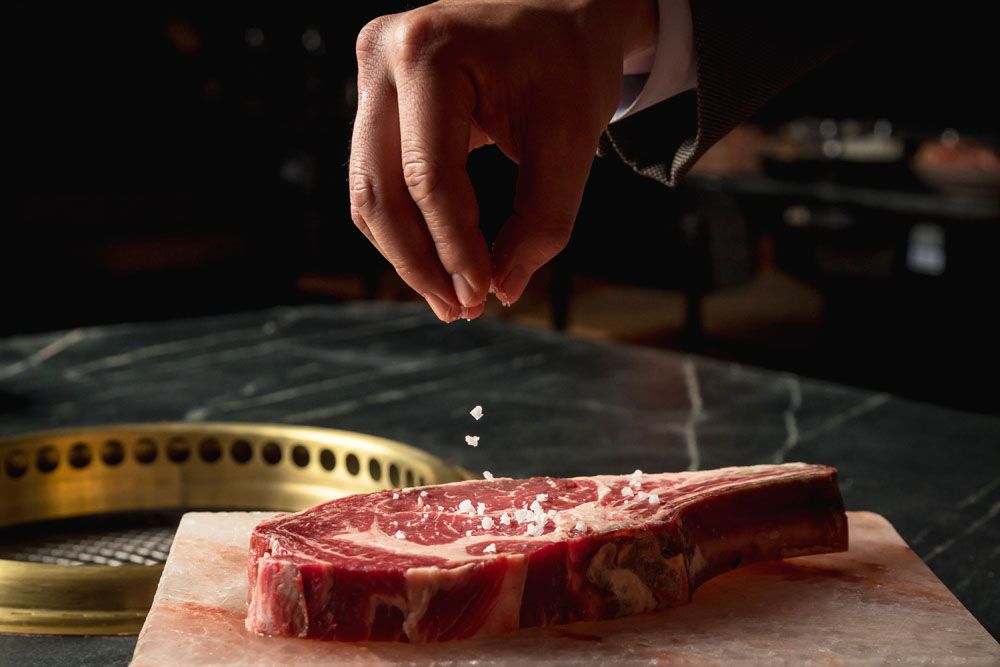 Steak being seasoned before it's grilled