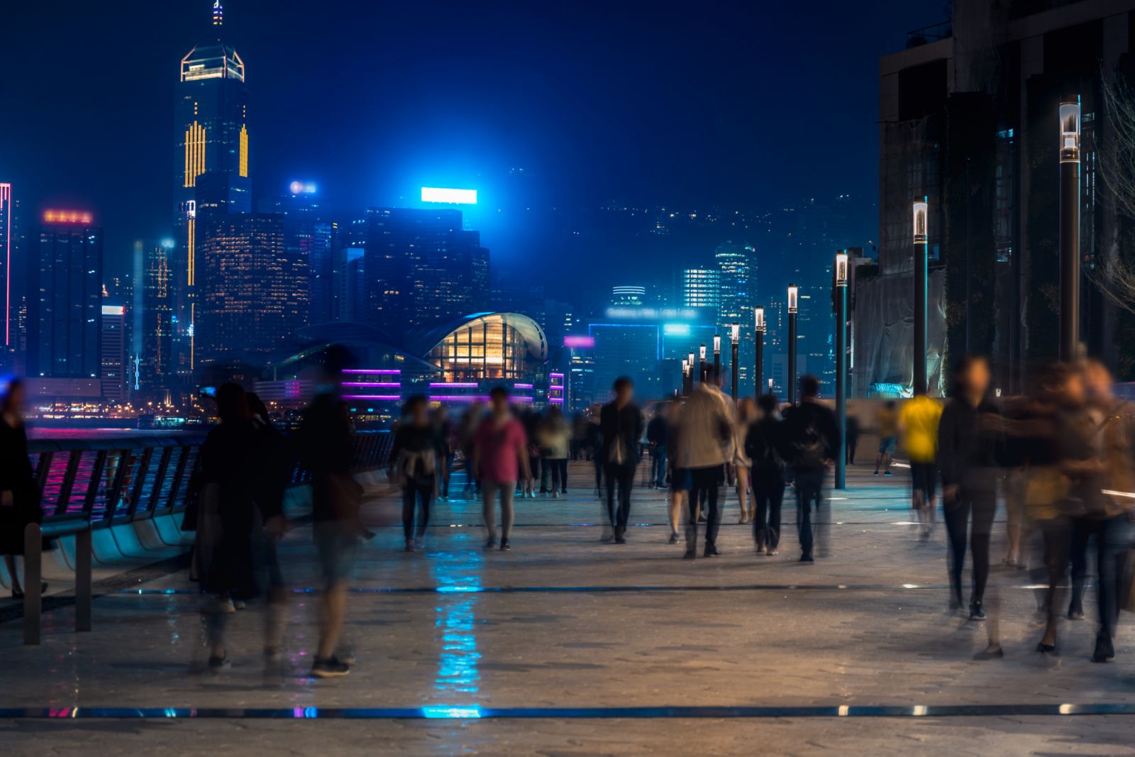 Hong Kong cityscape at night. Tourists walking on the waterfront