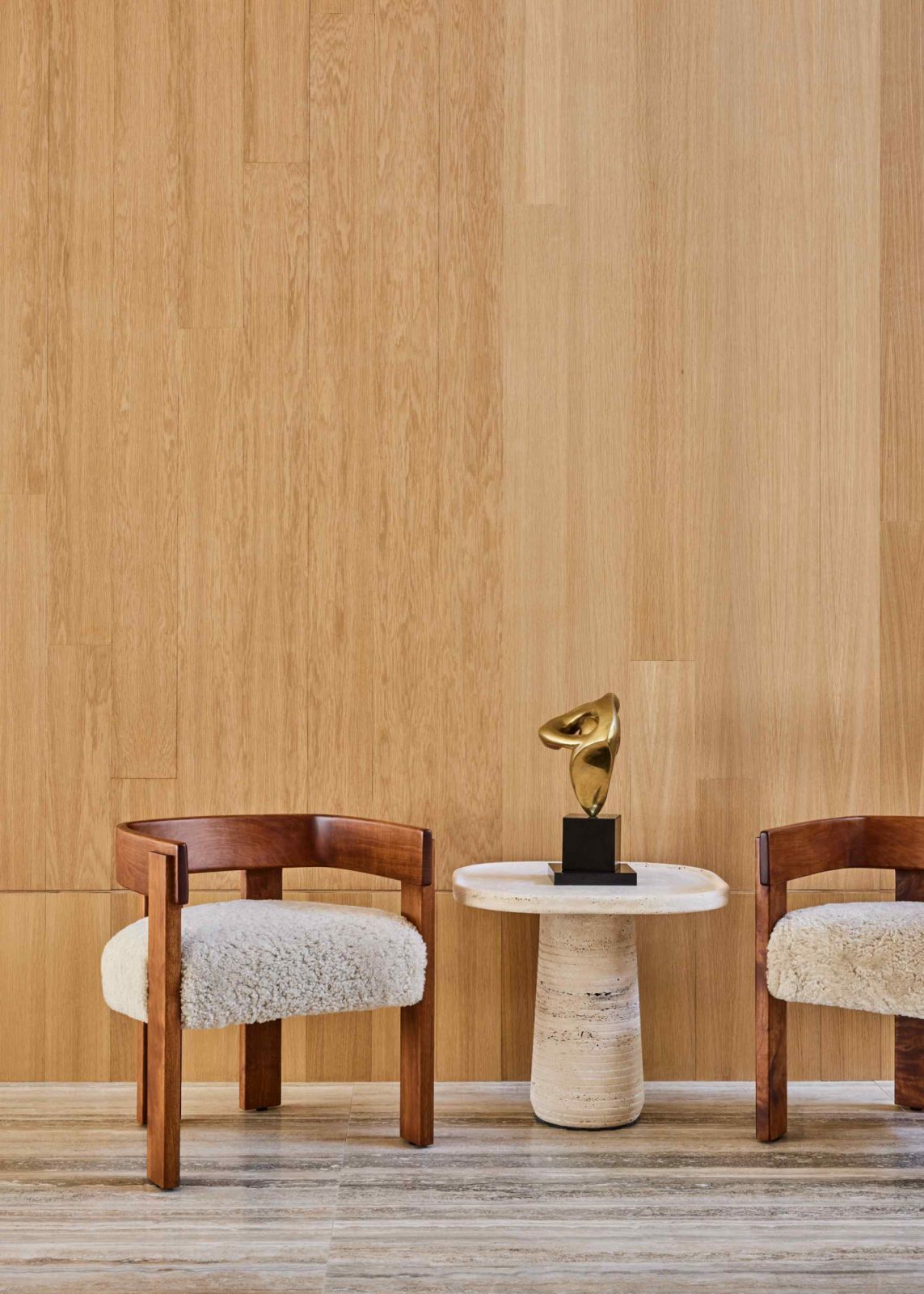 Vignette of shearling chairs, and a vintage sculpture atop the limestone side table
