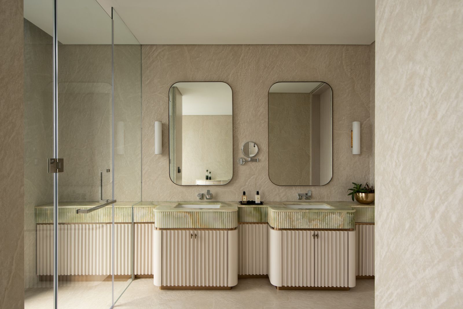 The bathroom contrasts a green onyx countertop with Dekton slabs