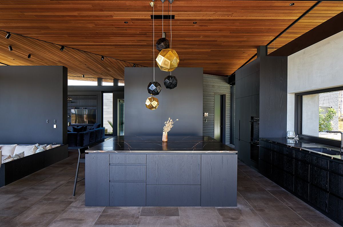 A large island counter and the sculptural pendant lights overhead create a striking focal point in the kitchen