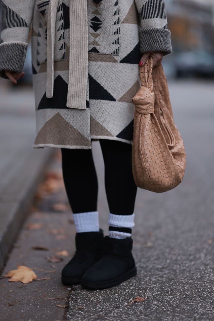 HAMBURG, GERMANY - NOVEMBER 13: Britta Becker seen wearing TWELVE by Britta Becker beige merino wool knit triangle pattern long coat, TWELVE by Britta Becker black leggings, Bottega Veneta beige leather Teen Jodie shoulder bag, white cotton socks and UGG black suede leather boots, on November 13, 2023 in Hamburg, Germany. (Photo by Jeremy Moeller/Getty Images)