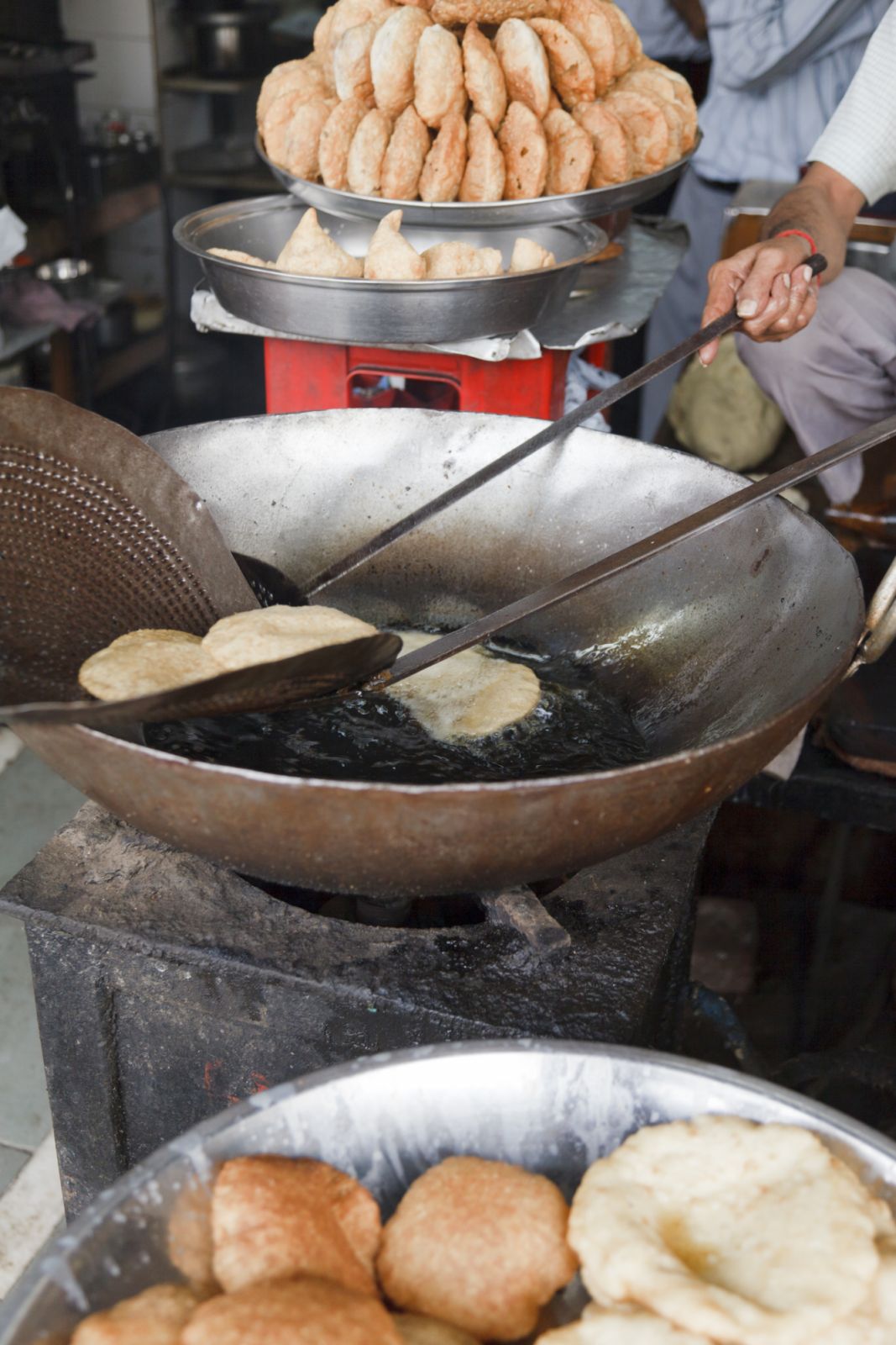 "Samosa patties being made by frying in oil. Street market near Chandni Chowk, Old Delhi, India."