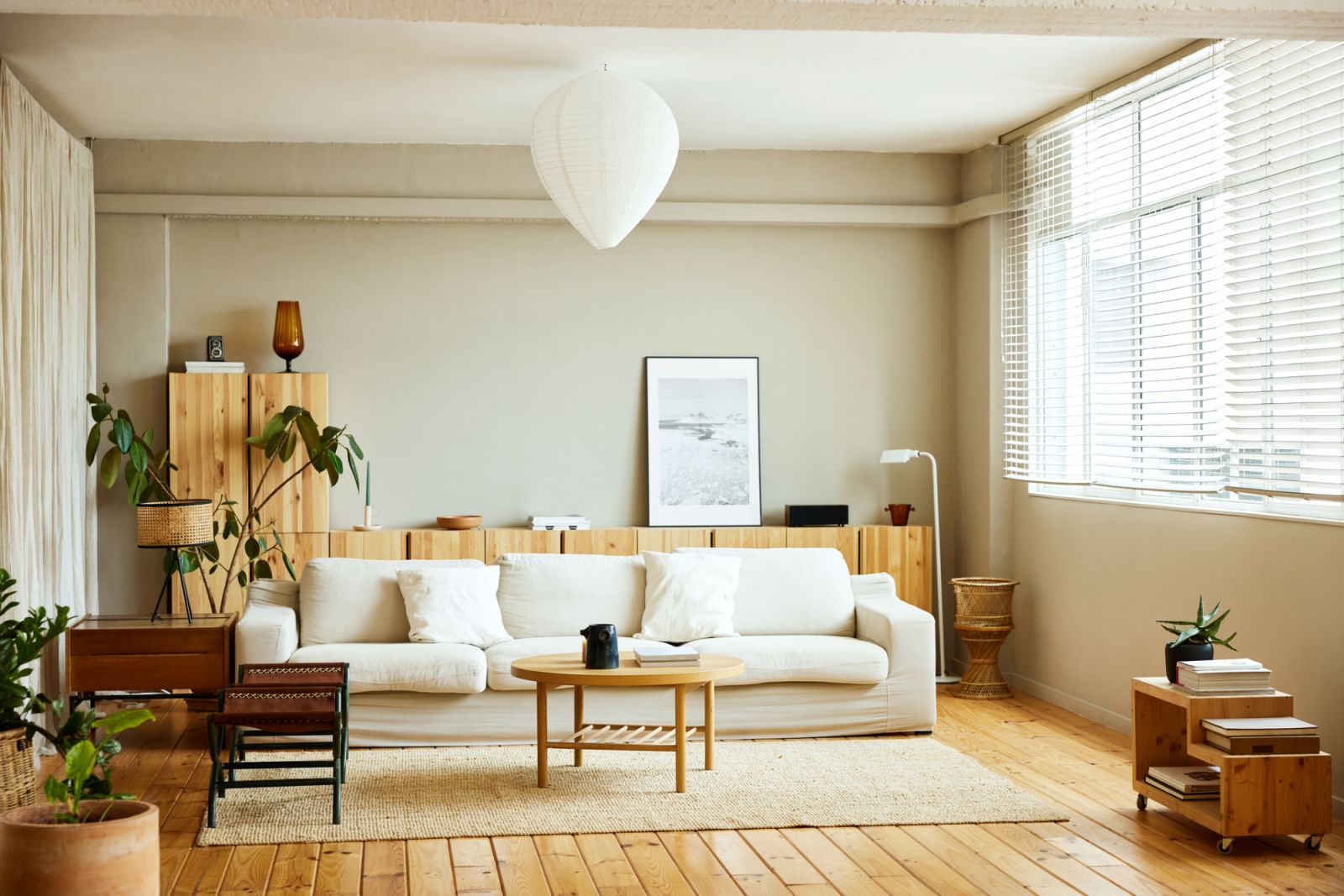 Sofa with coffee table by window in living room. Picture frame is on cabinet at home. Interior of modern bright apartment.