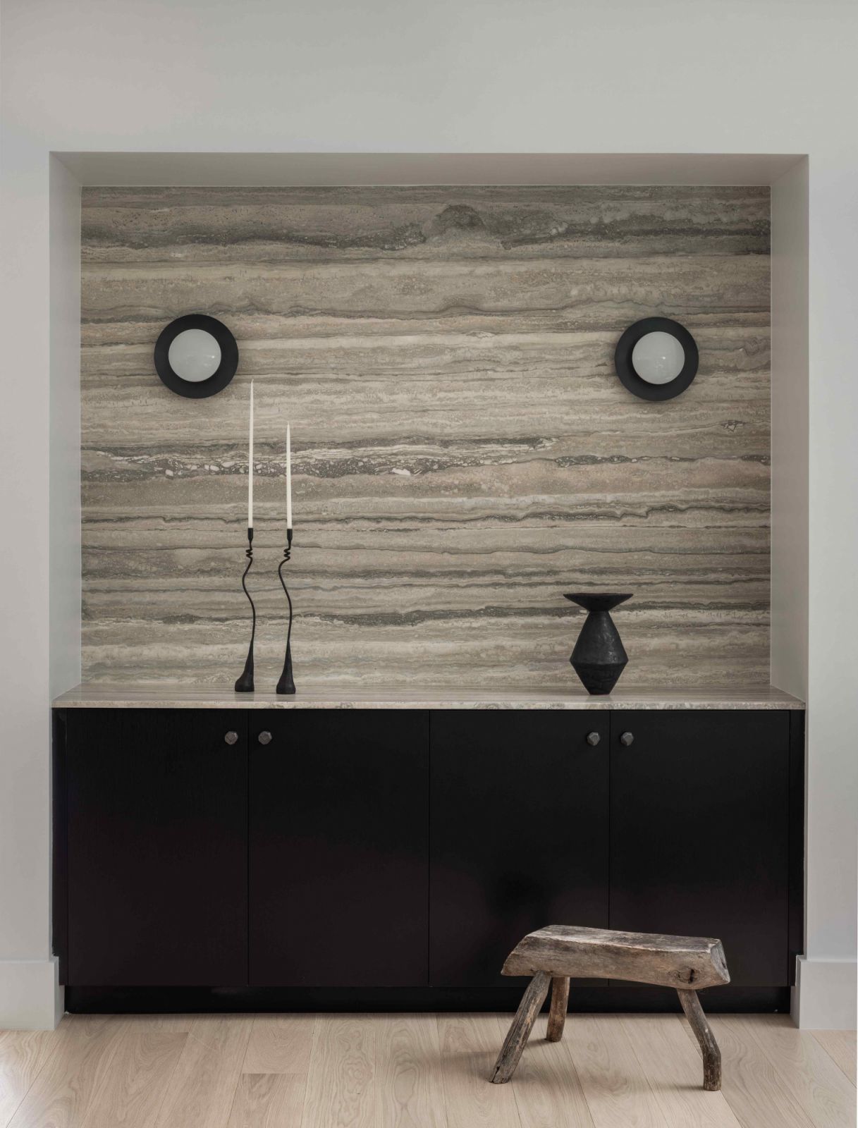 Custom dry bar of honed silver travertine added depth to the black oak doors