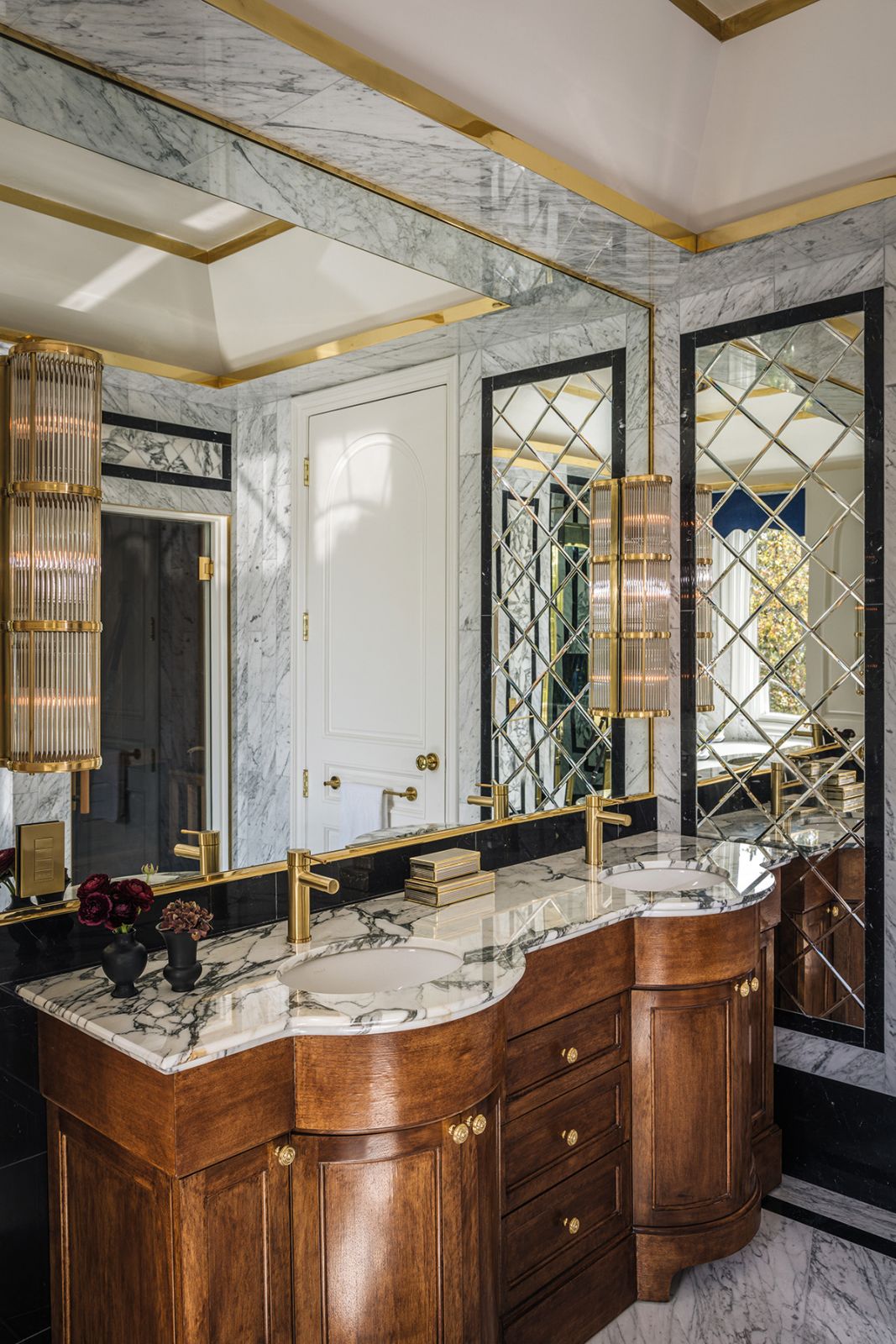 Murano glass sconces and the wooden vanity offer a nod to the Hollywood Regency style