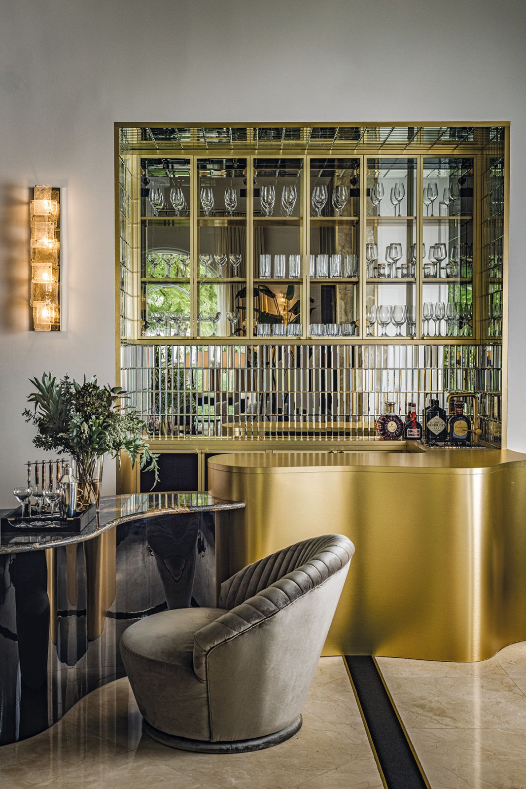 Crafted in brass and stone, the curved bar fixtures are paired with bespoke wall sconces made in Venice and custom swivel chairs in a plush velvet fabric