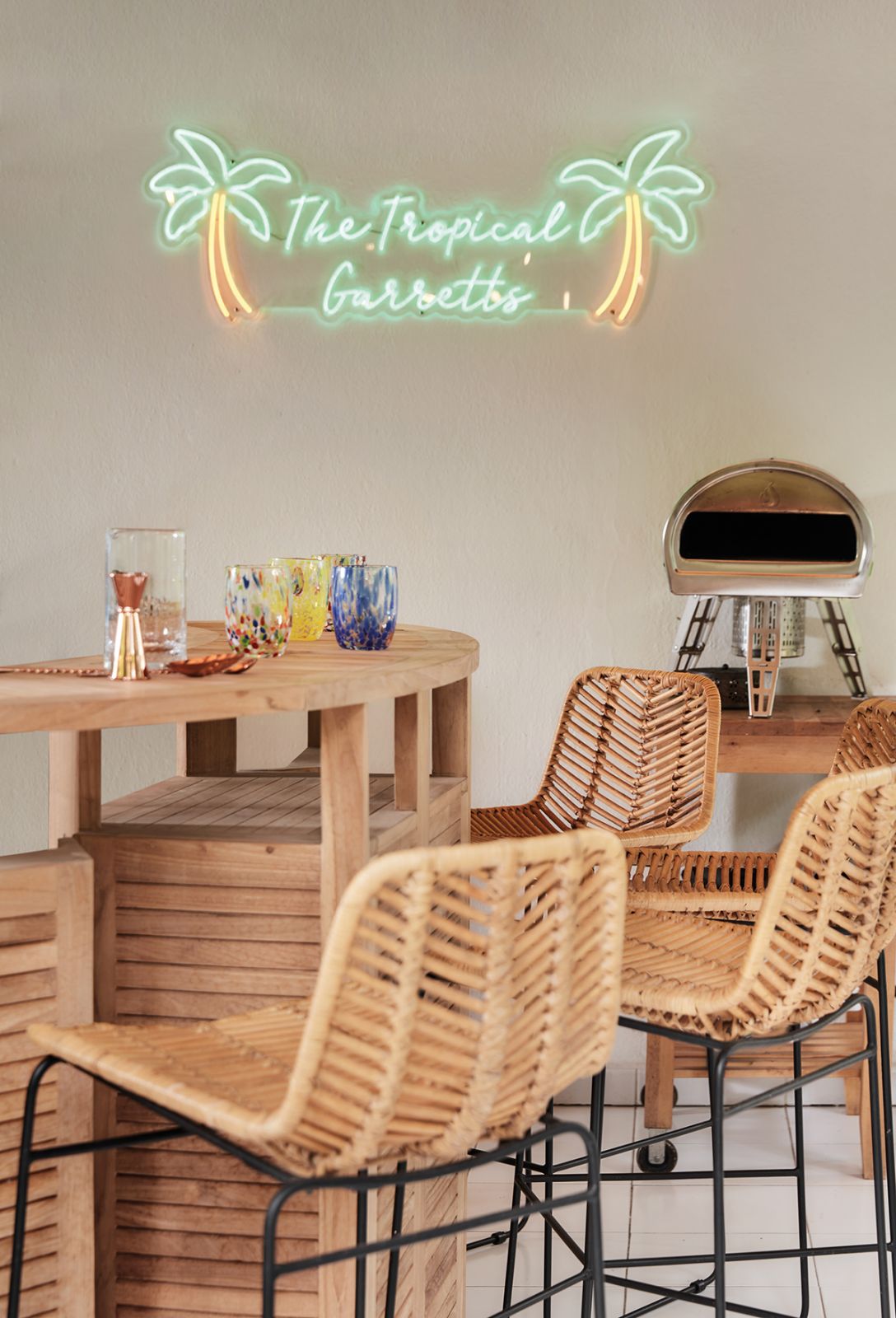 A delightful neon sign brings a resort-like feel to this beach bar-inspired seating area