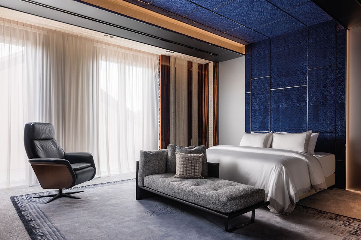 Extending up to the ceiling, the blue upholstered headboard makes a statement in the master bedroom