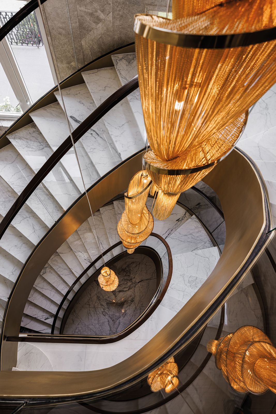 The custom chandeliers draw attention to the height and sculptural form of the spiral staircase