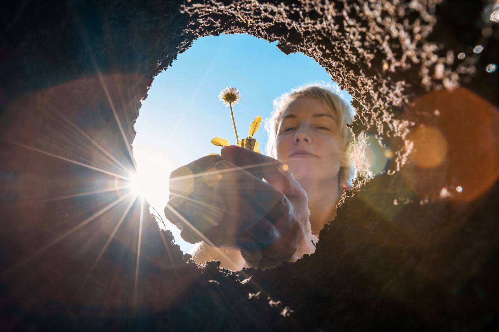 A young woman planting flower seedlings in the soil with a garden shovel on a sunny spring day. Gardening in your front or backyard.