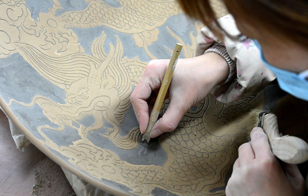 HANDAN, CHINA - JANUARY 22: An employee makes a dragon-themed ceramic plate at a ceramic factory ahead of the upcoming Chinese New Year, the Year of the Dragon, on January 22, 2024 in Handan, Hebei Province of China. (Photo by Hao Qunying/VCG via Getty Images)