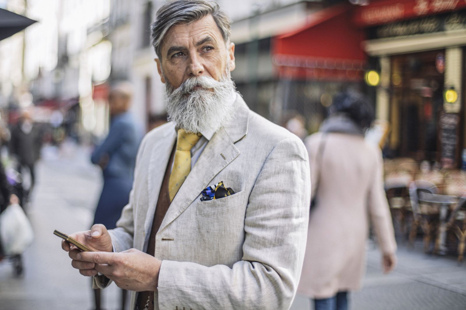Bearded mature man texting at the streets of Paris.