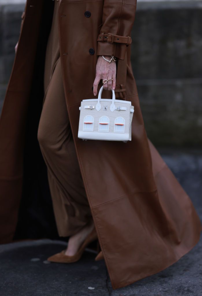 PARIS, FRANCE - JANUARY 24: Svitlana Degtyarenko is seen wearing a brown jumpsuit with a turtleneck, a wide black leather belt with golden details, a long cognac-colored coat, high brown pumps, black sunglasses with golden temples and a white Birkin handbag in croco design by Hermès during the Elie Saab Haute Couture Spring/Summer 2024 as part of Paris Fashion Week on January 24, 2024 in Paris, France. (Photo by Jeremy Moeller/Getty Images)