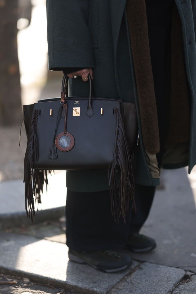 PARIS, FRANCE - JANUARY 20: Guest is seen outside Hermes show wearing a dark brown Hermes Birkin 35 with golden hardware and fringes during the Menswear Fall/Winter 2024/2025 as part of Paris Fashion Week on January 20, 2023 in Paris, France. (Photo by Jeremy Moeller/Getty Images)